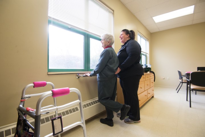 senior day services staff helping elderly woman look out window