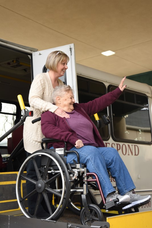 woman in wheelchair waving to staff at Senior Day Services