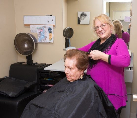elderly woman receiving haircut at senior day services